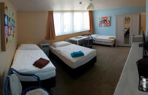 Cette chambre comprend deux lits, une table et un bureau. dans l'établissement Apartmentpension Am Krongut, à Potsdam