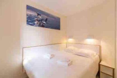 - une chambre dotée d'un lit blanc avec une photo sur le mur dans l'établissement Appart Climatisé 4 prsn / Vue Piscine & Vue Mer Cap Esterel, à Saint-Raphaël