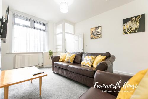 a living room with a brown couch and a table at Farnworth Contractor Accommodation in Farnworth