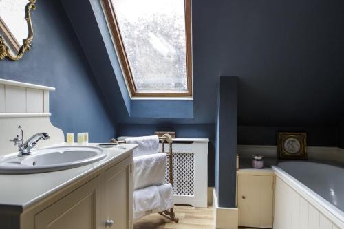 a blue bathroom with a sink and a tub at Rectory Manor in Lavenham