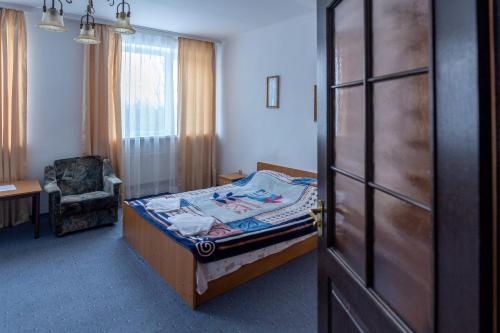 a bedroom with a bed and a chair and a door at Алексік in Truskavets