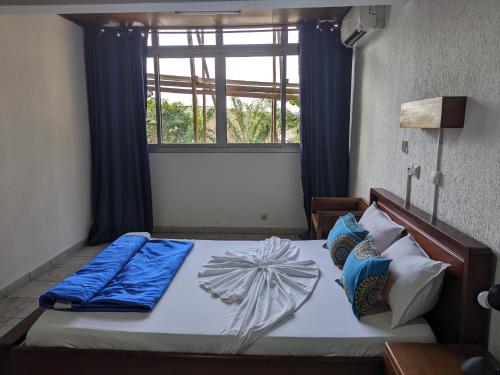 een slaapkamer met een bed met blauwe kussens en een raam bij Foyer du Marin in Douala