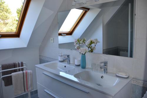 ein weißes Badezimmer mit einem Waschbecken und einem Spiegel in der Unterkunft L' ESCALE SINAGOTE Chambre d'hôtes in Séné