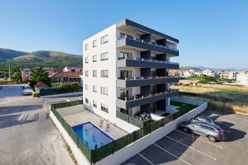 an apartment building with a swimming pool in a parking lot at Sore in Trogir