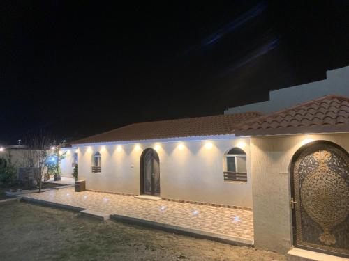 Un bâtiment blanc avec des lumières allumées la nuit dans l'établissement شاليه, à Rusibah