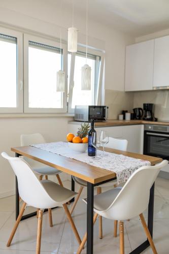 a kitchen with a wooden table and white chairs at Sore in Trogir