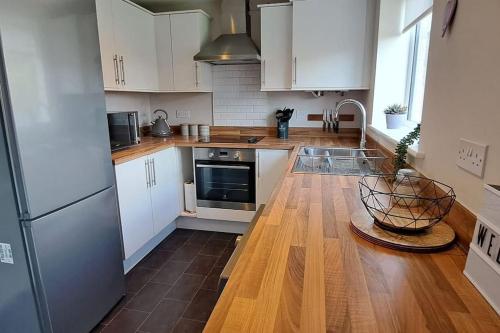 uma cozinha com armários brancos e piso em madeira em Lovely 2 Bed, detached home. em Seacroft