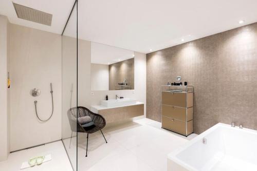 a bathroom with a shower and a sink and a chair at Luxus Wohnung mit Panoramablick in Mondsee