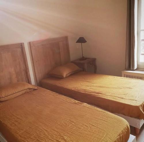 une chambre avec deux lits et une lampe et une fenêtre dans l'établissement Maison paisible au cœur des corbieres, à Saint-Laurent-de-la-Cabrerisse