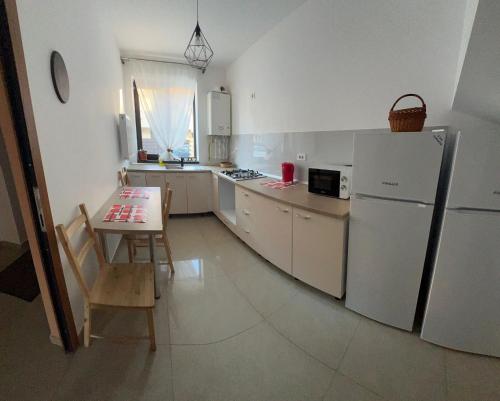 Il comprend une cuisine équipée d'une table et d'un réfrigérateur blanc. dans l'établissement Vila Nova Residence, à Popeşti-Leordeni