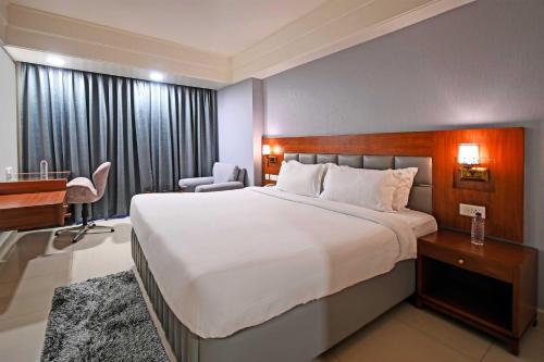 um quarto de hotel com uma cama grande e uma secretária em Palette - Madhapur em Hyderabad