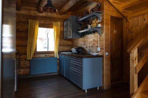 una cocina con una isla azul en una cabaña de madera en Green Cottage, en Râșnov