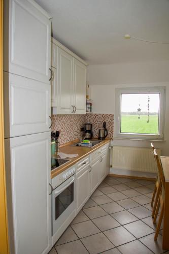 a kitchen with white cabinets and a window at Idyllische Ferienwohnung in Seefeld in Norderaussendeich