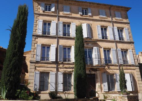 Chambres d'Hôtes Le relais des marmottes في Lagnes: مبنى حجري كبير مع نوافذ مغلقه بيضاء