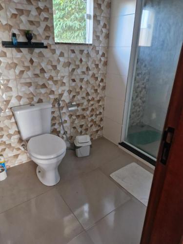a bathroom with a toilet and a glass shower at Suite independente com garagem prox à praia da Vila in Saquarema