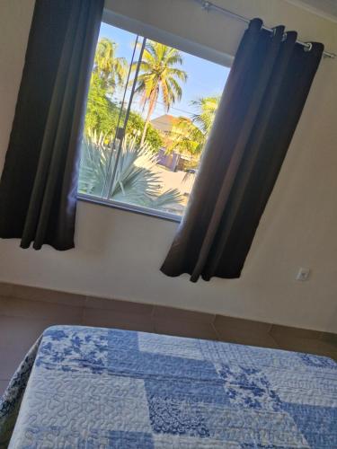 a bedroom with a window with a view of a palm tree at Suite independente com garagem prox à praia da Vila in Saquarema