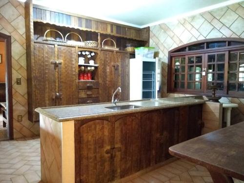 una cocina con armarios de madera y fregadero en Chácara Santa Rita en São Pedro
