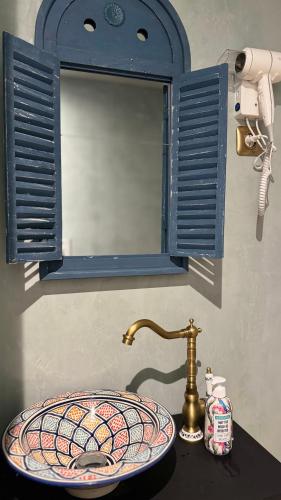 un lavabo dans une salle de bain avec une fenêtre bleue et un miroir dans l'établissement Évasion Emeraude, à Roubaix