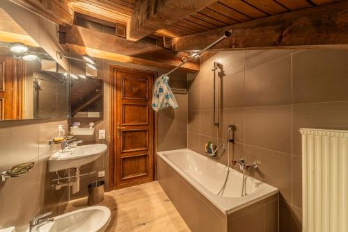 a bathroom with a tub and a sink and a bath tub at Chesa Ste Attic - Celerina in Celerina