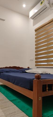 Un dormitorio con una cama azul y una ventana en JAWAN VILLA, en Ernakulam