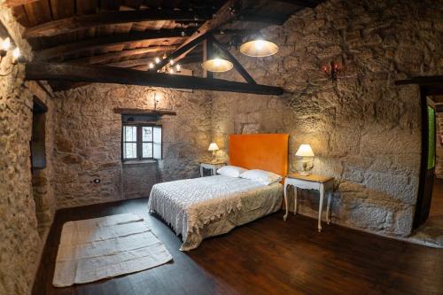 um quarto com uma cama numa parede de pedra em Os Queixeiros Rural House em Chantada