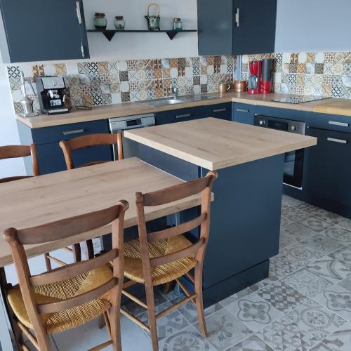 une cuisine avec des placards bleus et une table et des chaises en bois dans l'établissement Appart Sion face mer, à Sion-sur-lʼOcéan