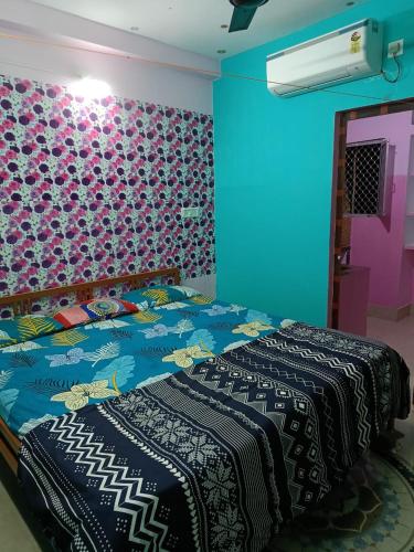 ein Schlafzimmer mit einem Bett mit einer farbenfrohen Wand in der Unterkunft JHARANA GUEST HOUSE in Puri