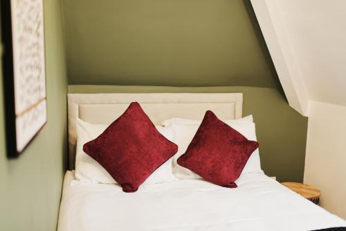 a bed with two red pillows on it at Garmoyle Road Flat 3 in Liverpool