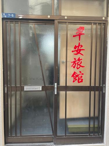 a glass door with a sign on top of it at 平安旅馆和风 in Tokyo