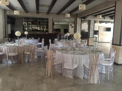 een grote feestzaal met witte tafels en stoelen bij La Strada in Onești