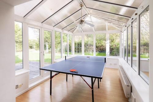 a ping pong table in a room with windows at Ping-Pong Paradise in Crawley