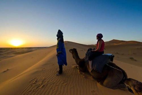 two people riding a camel in the desert at Spacious Apartment with Motorcycle Garage, Free Parking, and Air Conditioning in Er Rachidia