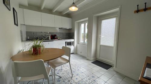 cocina con mesa de madera y armarios blancos en La maisonnette de Julien - 3 étoiles, en Ceyrat