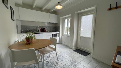 una cucina con un tavolo in legno e mobili bianchi di La maisonnette de Julien - 3 étoiles a Ceyrat