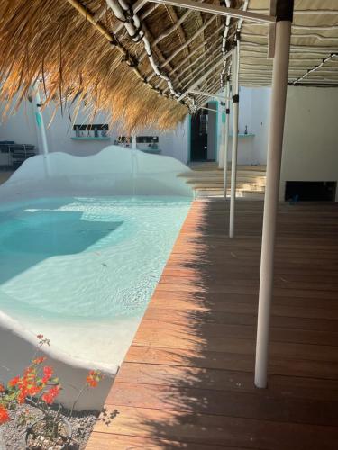 a swimming pool with a straw roof and a boardwalk at TANAWU AIRPORT HOTEL LOMBOK in Praya