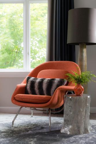 a living room with a orange chair and a lamp at Field Guide Lodge in Stowe