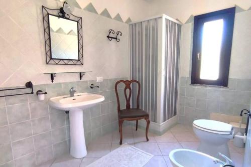 een badkamer met een wastafel, een toilet en een stoel bij Villa Susy Solanas -IUN R5389 in Solanas