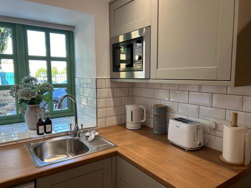 um balcão de cozinha com um lavatório e um micro-ondas em The Old Stables em Northampton