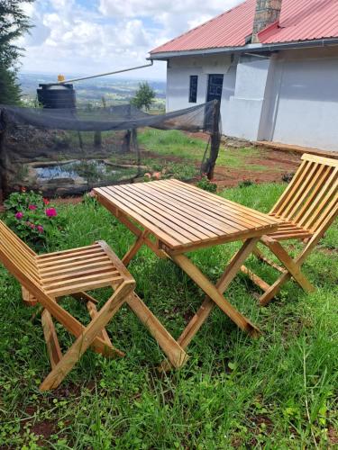 una mesa de picnic de madera y 2 sillas en el césped en Aberdare white camp house kenya, en Ndaragwa