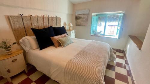 een slaapkamer met een bed met kussens en een raam bij Alojamiento La Casa del Pintor in Almonaster la Real