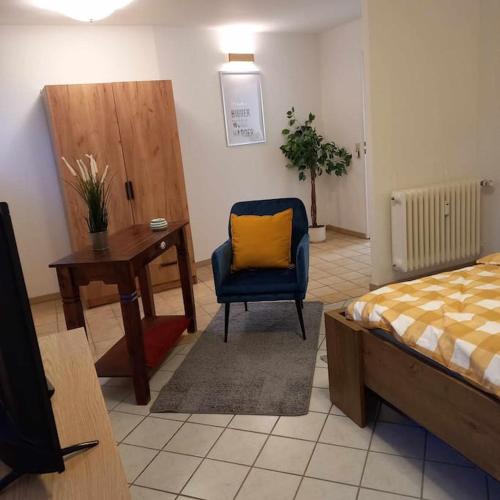ein Schlafzimmer mit einem Bett und einem Stuhl mit einem gelben Kissen in der Unterkunft Zwei-Zimmer-Appartement Essen in Essen