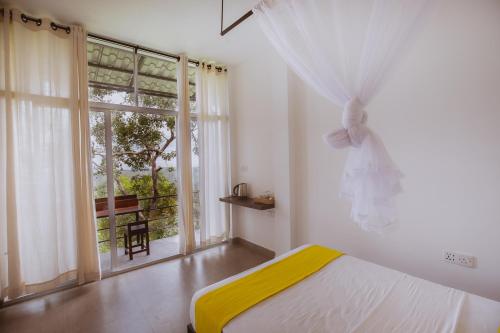 a bedroom with a bed and a large window at Treehouse Chalets in Belihuloya