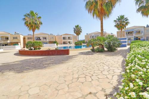 a resort courtyard with palm trees and a swimming pool at Mermaid Holiday Apartments in Mandria