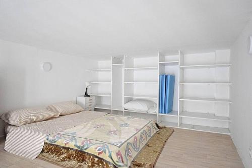 - une chambre avec un lit et des étagères blanches dans l'établissement Beau studio mezzanine meublé, à Courbevoie