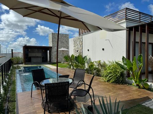 a patio with a table and chairs and an umbrella at Castelo Boulevard in Tibau do Sul