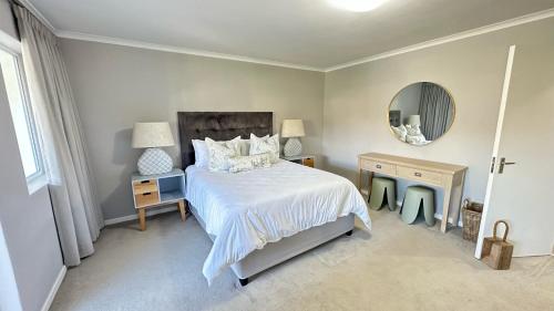 una camera con letto bianco e specchio di Greenpoint Mews 17, Plettenberg Bay a Plettenberg Bay