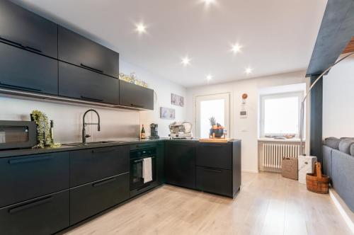 a kitchen with black cabinets and a sink at Contrada della Fontana Luxury Apartment in Levico Terme