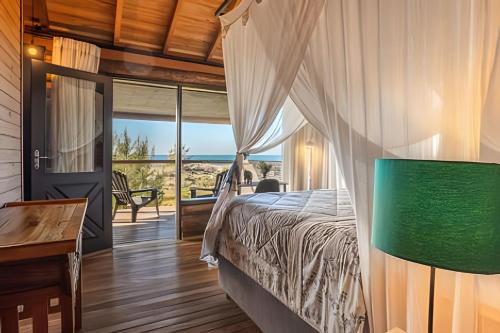 a bedroom with a bed and a view of the ocean at Villa Sayuri in Barra de Ibiraquera