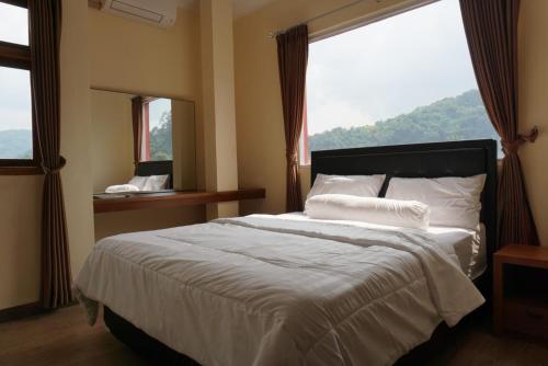 a bedroom with a large bed with a large window at Cipada Guesthouse syariah in Sumedang