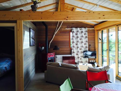 ein Wohnzimmer mit einem Sofa in einem Holzhaus in der Unterkunft Gîte Les Cigognes in Orchamps-Vennes